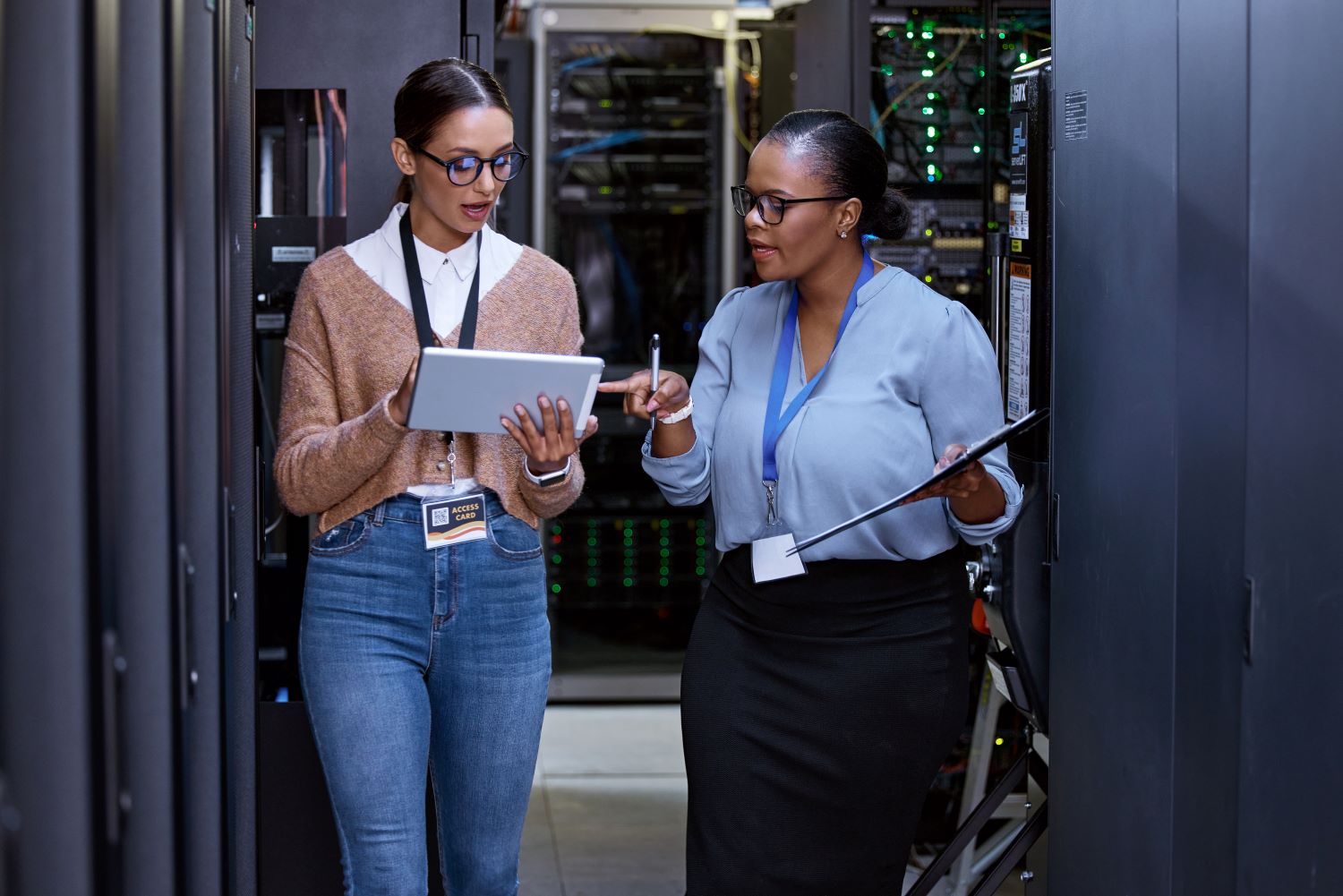 two women technology workers walking through a server room