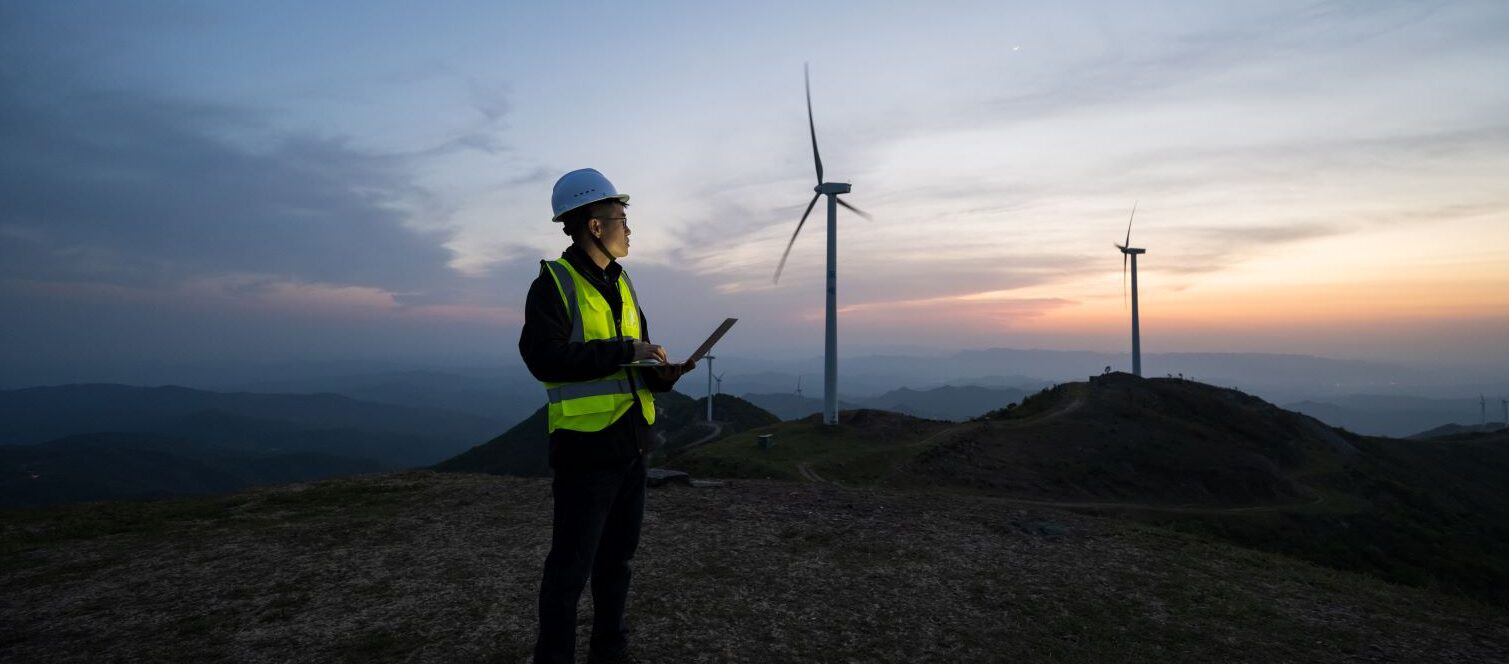 worker surveying wind turbines at dusk