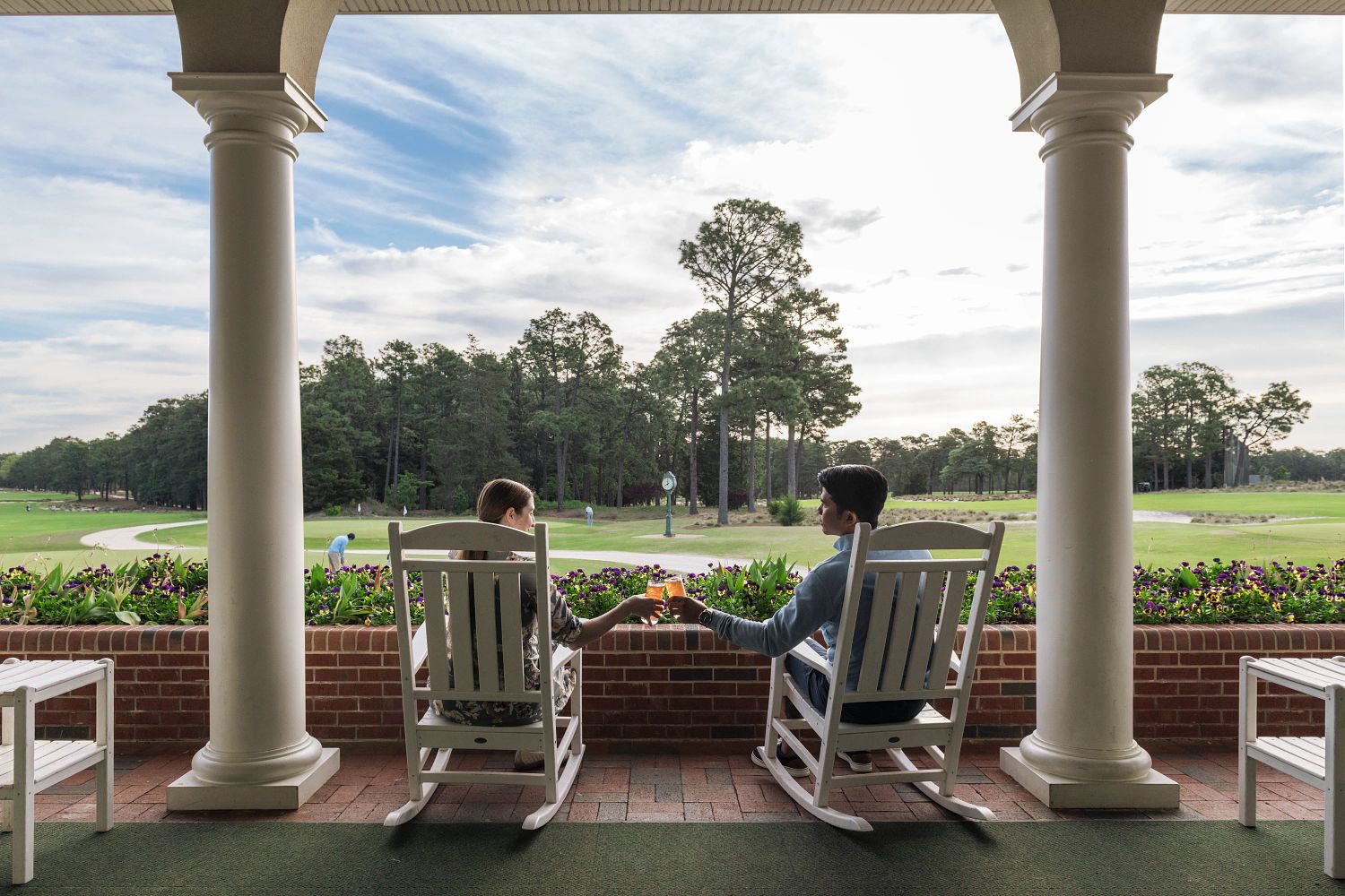 couple sitting in rocking chairs overlooking golf course