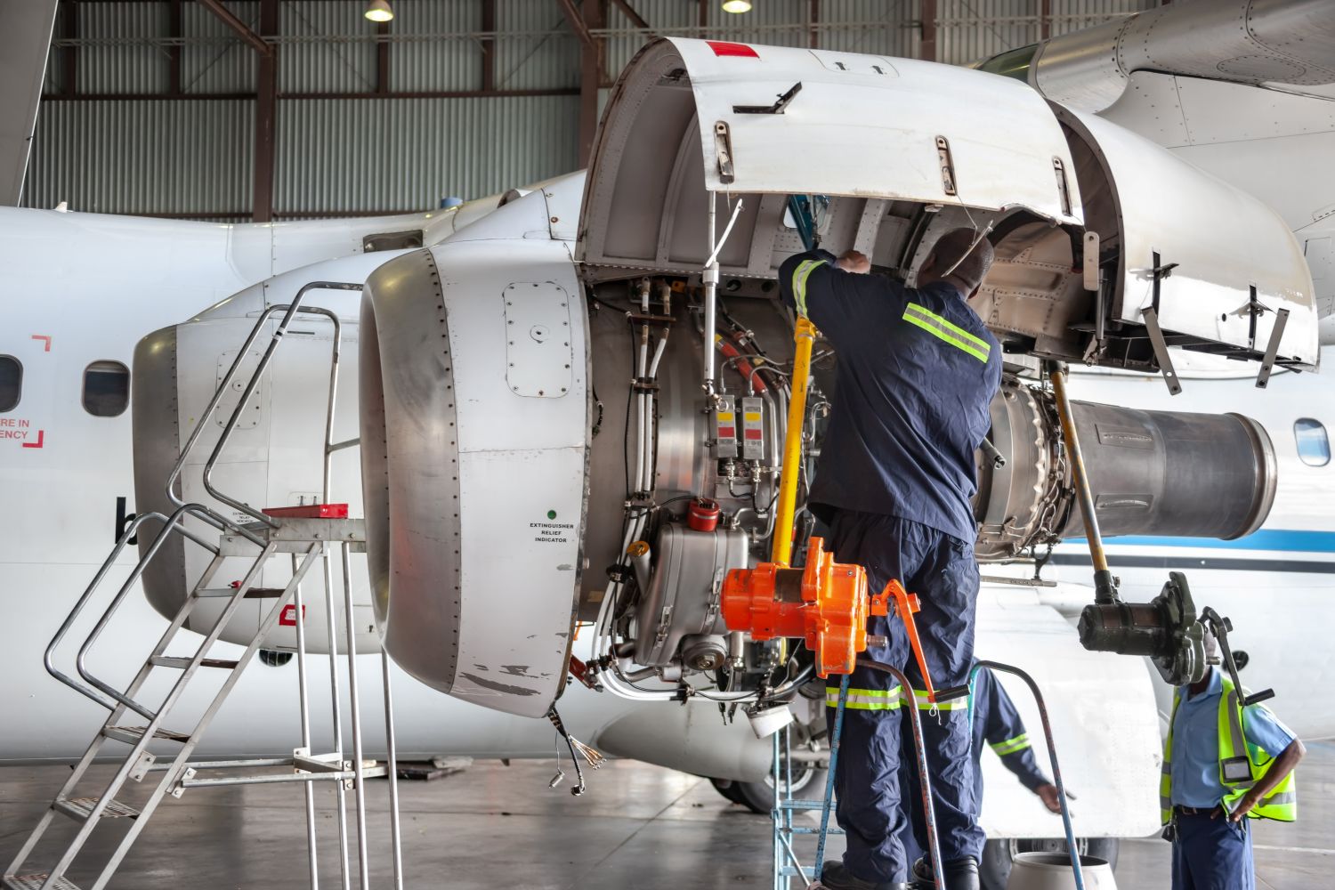 worker under hood of jet engine